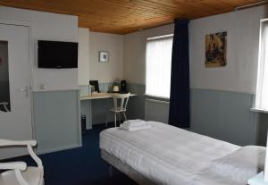 a bedroom with a bed and a desk with a computer at Hotel Verhoeven in Uden