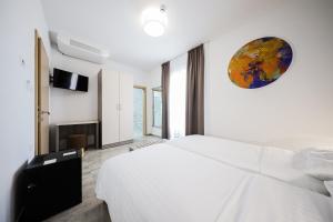 a bedroom with a white bed and a clock on the wall at Hotel Lucija in Posedarje