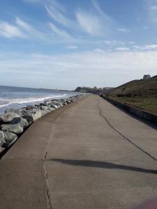 an empty road next to the ocean with rocks at Bramblewick in Whitby +11 photos