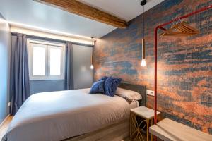 ein Schlafzimmer mit einem Bett und einer Ziegelwand in der Unterkunft Apartamentos Pensua Sisargas in Malpica