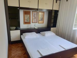 ein Schlafzimmer mit einem Bett mit weißen Laken in der Unterkunft Apartman Marija in Jadranovo