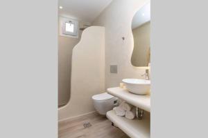 Un baño con lavabo, inodoro y espejo. en Arktos Luxury Apartment, en Naxos Chora 39 fotos más