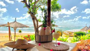 Casa na Praia Tofo- beach front hotel في بارايا دو توفو: طاولة مع أحذية وكأس من النبيذ على الشاطئ