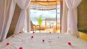 Casa na Praia Tofo- beach front hotel في بارايا دو توفو: غرفة نوم بسرير مع اطلالة على الشاطئ