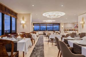 a restaurant with white tables and chairs and windows at Ramada by Wyndham Nigde in Nigde
