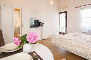 a white room with a bed and a table with flowers at Apartments & Rooms Darrer in Poreč