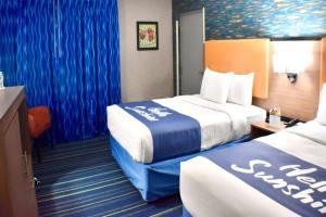 a hotel room with two beds and blue curtains at Days Inn by Wyndham Wayne in Wayne