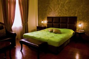 Un dormitorio con una cama verde con una silla y una ventana en Andromeda Suites, en Nauplia