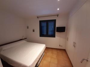 a bedroom with a white bed and a window at Cal Montaner in Cadaqués