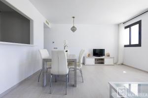 uma sala de jantar com uma mesa e cadeiras brancas em Estepona Sunsets - Modern 3-BR Beachside Apartment em Estepona
