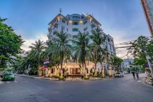 a large white building with palm trees in front of it at Cocochine Da Nang in Danang