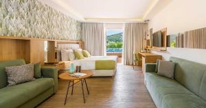 a hotel room with a bed and two green couches at Dolce by Wyndham Athens Attica Riviera in Vravrona