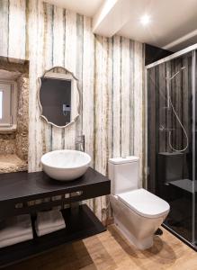 ein Badezimmer mit einem WC, einem Waschbecken und einem Spiegel in der Unterkunft Apartamentos Pensua Sisargas in Malpica