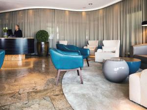 a lobby with blue chairs and a piano at Mövenpick Hotel Lausanne in Lausanne