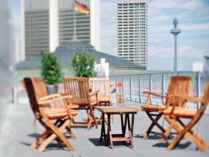 eine Gruppe Stühle und ein Tisch auf dem Balkon in der Unterkunft Mövenpick Hotel Frankfurt City Messe in Frankfurt am Main