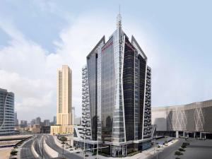 a tall glass building in a city at Mövenpick Hotel Apartments Downtown Dubai in Dubai