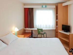 a hotel room with a bed and a desk and a window at ibis Douala in Douala