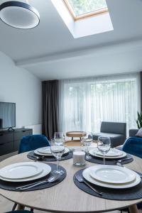 a table with plates and wine glasses on it at Apartment Hotel Laisve in Druskininkai