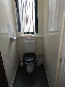 a bathroom with a toilet with a black seat and a window at The Garnett in Blackpool