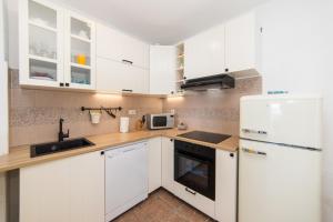 a kitchen with white cabinets and a white refrigerator at Apartmani Kala in Podgora
