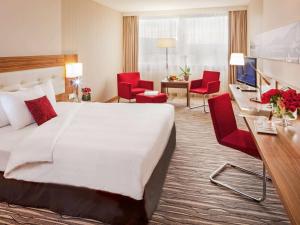 um quarto de hotel com uma cama grande e cadeiras vermelhas em Mövenpick Hotel & Casino Geneva em Genebra