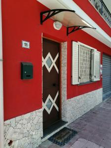 un bâtiment rouge avec une porte et une fenêtre dans l'établissement Casetta Rosso Tulipano, à Santa Teresa di Riva