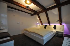 a bedroom with a white bed with purple lighting at Soleiado Hotel in Bietigheim-Bissingen