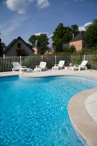 une piscine avec des chaises blanches et une clôture dans l'établissement Hostellerie Du Château Les Muids, à La Ferté-Saint-Aubin