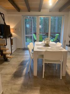 een witte tafel en stoelen in de woonkamer bij Domek wypoczynkowy w lesie nad jeziorem in Ocypel