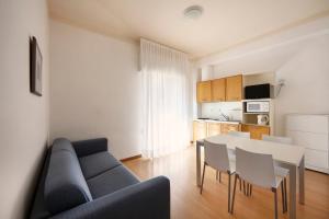 ein Wohnzimmer mit einem blauen Sofa, einem Tisch und Stühlen in der Unterkunft Aparthotel La Pineta in Lido di Jesolo