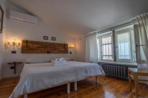 a bedroom with a bed with white sheets and two windows at Mansarda 64 in Castelnuovo del Garda