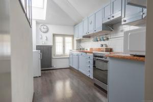 a kitchen with white cabinets and a clock on the wall at Mansarda 64 in Castelnuovo del Garda