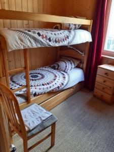 two bunk beds in a room with a chair at Chez LIZON in Barcelonnette