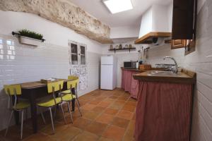 a kitchen with a table and yellow chairs at Cueva de la Abuela María in Alcalá del Júcar