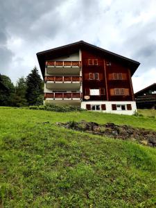 ein Gebäude auf einem Hügel mit einem Grasfeld davor in der Unterkunft Apartment 2,5 Zimmer im Ferienhaus Damian in Braunwald