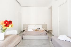 a white bedroom with a bed and a vase of flowers at Lux Caracciolo in Naples