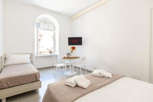 Cette chambre blanche comprend deux lits et une table. dans l'établissement Lux Caracciolo, à Naples