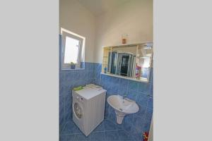 uma casa de banho em azulejos azuis com um lavatório e um espelho em Adriatic em Mali Lošinj