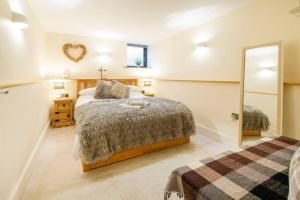 ein Schlafzimmer mit einem großen Bett und einem Spiegel in der Unterkunft New Loos Cottage, Old School Court in Stow on the Wold