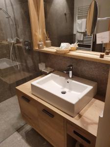 bagno con lavandino bianco e specchio di Garni Hotel Mezdi a Selva di Val Gardena