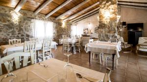 un restaurante con mesas y sillas blancas y paredes de piedra. en La Casa de la Estación, en Sarrión