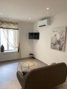 a living room with a couch and a tv on the wall at Le Nid du Faubourg in Beaune
