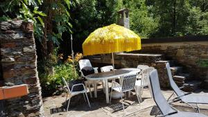 eine Terrasse mit einem Tisch, Stühlen und einem Sonnenschirm in der Unterkunft Casa Accogliente Valle Cannobina in Le Biuse