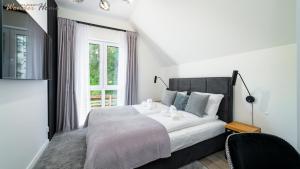 a bedroom with a large white bed with a window at Wonder Home - Domki górskie wolnostojące z prywatnymi tarasami - zielona okolica in Karpacz
