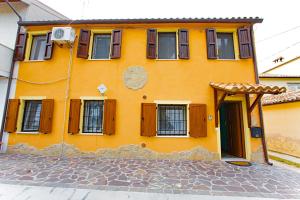 a yellow house with wooden windows and a door at Eden Lilli B&B in La Pieve