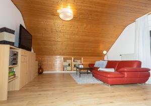 Ferienwohnung Apfelblüte في Burgbernheim: غرفة معيشة مع أريكة حمراء وسقف خشبي