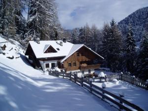 a log cabin in the snow with a fence at Leithäusl in San Lorenzo di Sebato