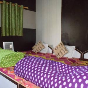 The Sanatan- Bamboo Huts في جوشيماث: غرفة نوم مع سريرين مع ملاءات ومخدات ملونة