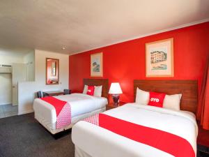 a hotel room with two beds with red walls at Capital O Padre Island Corpus Christi in Corpus Christi
