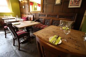 un restaurante con mesas de madera, sillas y copas de vino en The Angel in Wootton Bassett, en Royal Wootton Bassett
